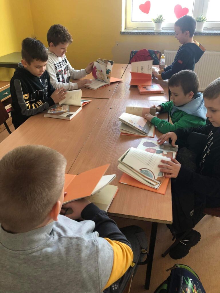 Na zdjęciach dzieci ze Szkoły Podstawowej w Wierzbnie czytające książkę 