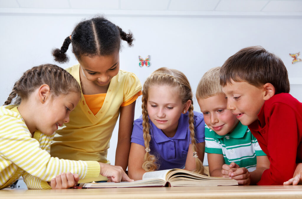 Pięcioro uczniów, trzy dziewczynki i dwóch chłopców czytają książkę