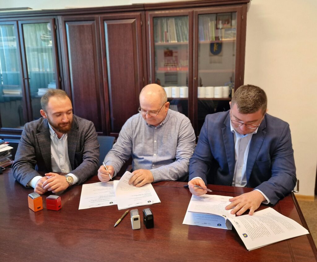 trzech mężczyzn podpisujących dokumenty prztybiurku