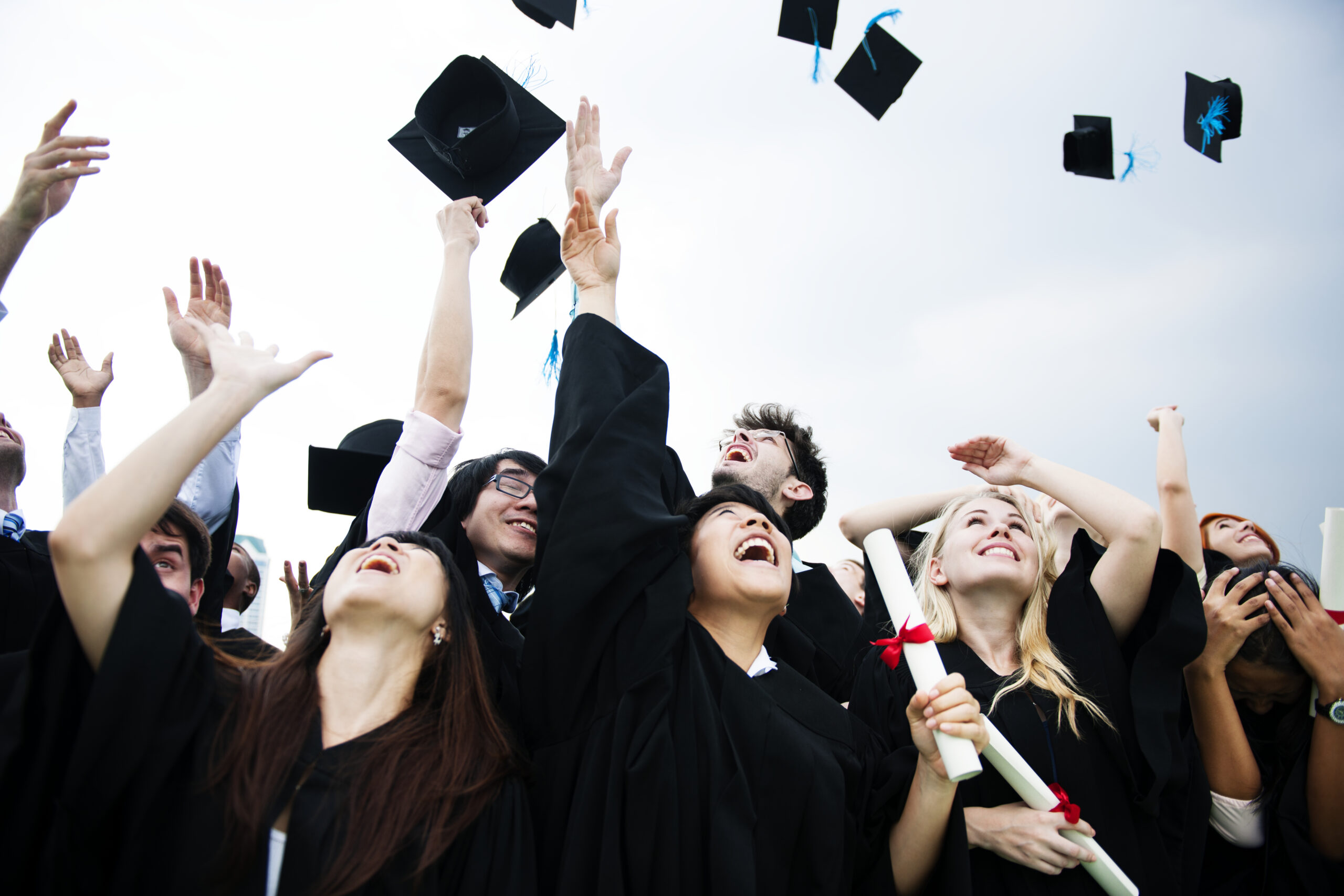 Free photo group of diverse grads throwing caps up in the sky