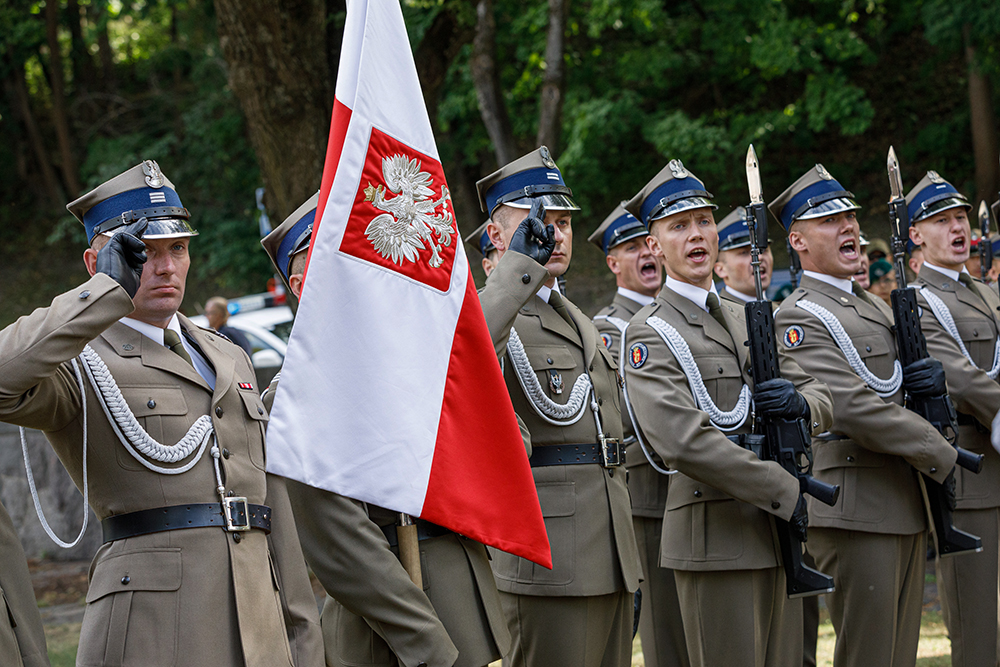 Na zdjęciu żołnierze stojący w szeregu z flagą biało - czerwoną