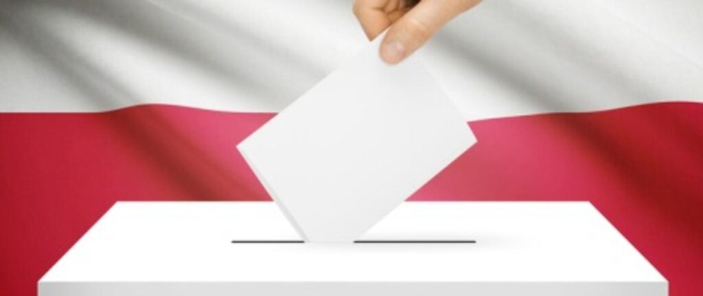 ręka wsadzająca kartke do urny wyborczej w tle biało-czerwona flaga