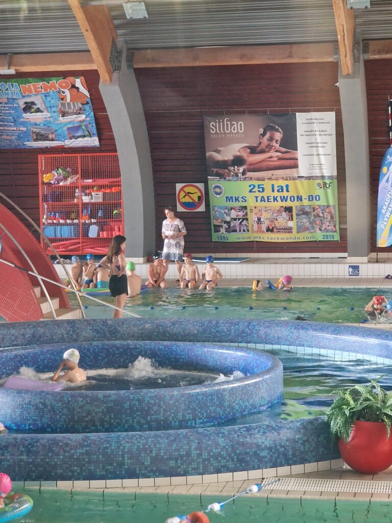 Na zdjęci8ach dzieci w grupach pływające na basenie, logo Ministerstwa Sportu