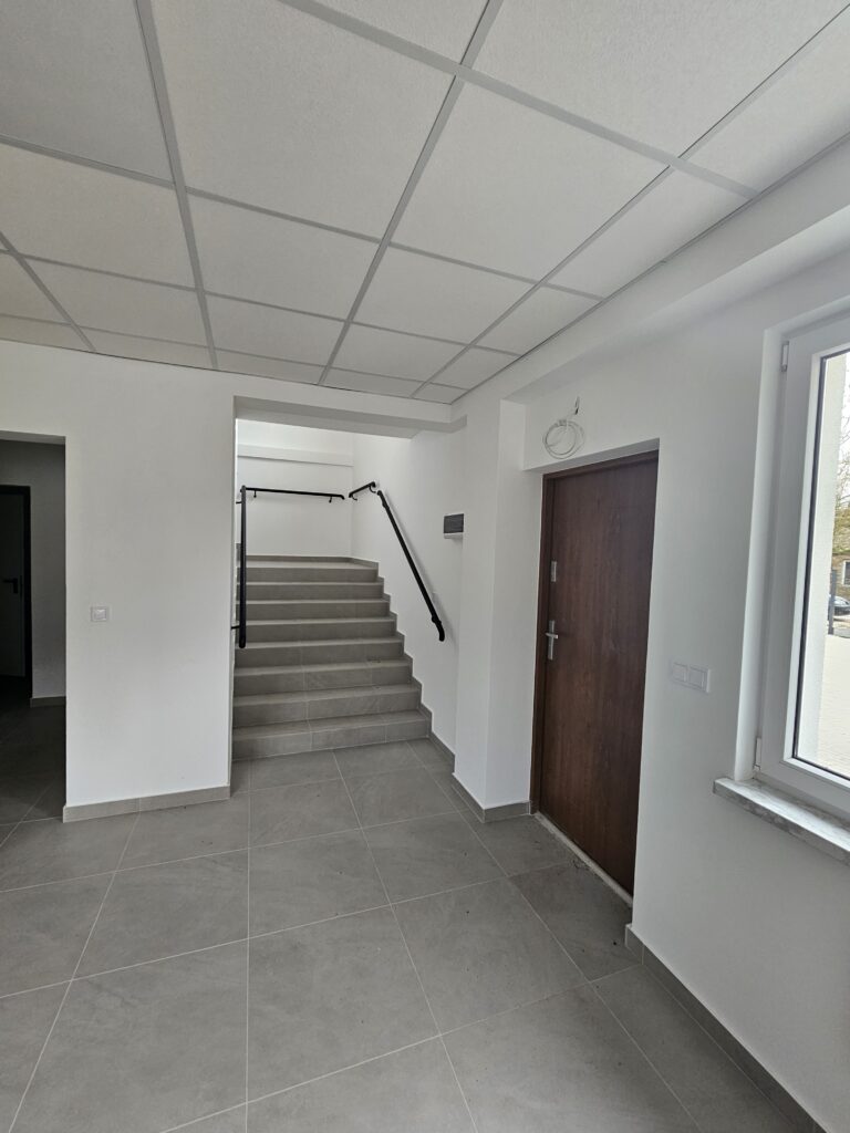 Na obrazku zewnętrznym, który jest podłączony do instalacji, są drewniane schody na wysokie piętro. Podłoga jest położona w kafelkach, które zawierają spójny kontrast z dodatkowym wnętrzem.