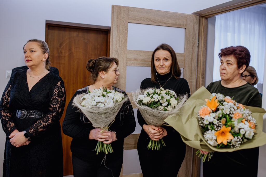 Na obrazku jest grupa kobiet, które trzymają w rękach bukiety kwiatów, zamknięcie przed drzwiami. Są ubrane w końcowe stroje, a tło za ich dekoracyjną domową lub ceremonijną atmosferę.