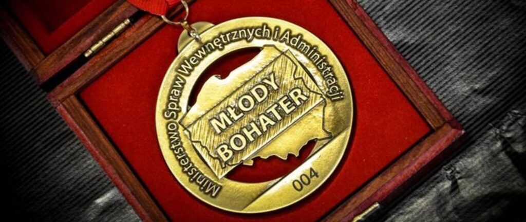 Na obrazku pojawia się medal z napisem „Młody bohater”, który jest w eleganckim, czerwonym. Medal prawdopodobny jest jako podtrzymywany dla młodej osoby za wyjątkowe lub wstępne.