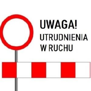 Znaki drogowe ostrzegają o utrudnieniach w ruchu. Na białym tle widoczny jest czerwony znak zakazu. Pod spodem biało-czerwony szlaban.