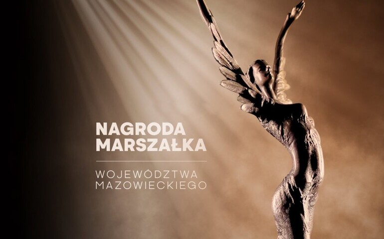 Posąg anioła na brązowym tle, z napisem Nagroda Marszałka Województwa Mazowieckiego. Światło pada z góry.
